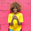 Frau mit Handy steht vor Wand in Pink