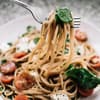 Weißer Teller mit Pasta, Tomaten und Spinat