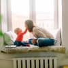 Baby haelt Gesicht von jungen Frau