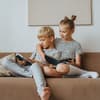 Große Schwester mit kleinem Bruder im Arm auf der Couch