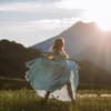 Frau tanzt im Kleid auf der Wiese bei Sonnenschein 