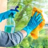 Fenster putzen: Hände mit Putzhandschuhen säubern eine Fensterscheibe
