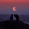 Drei Leute sitzen vor Supermond