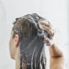 Frau wäscht sich die Haare mit Shampoo