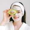 Frau mit Gesichtsmaske und Avocado
