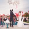 Brautpaar steht vor Pool und lässt Luftballons steigen