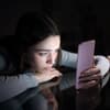 Frau guckt traurig auf ihr Smartphone