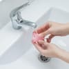 Menstruationstasse unter Wasserhahn reinigen