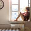 Frau sitzt alleine am Fenster