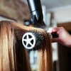 Frau werden die Haare auf einer Rundbürste geföhnt
