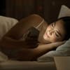 Sexting: Frau mit Handy im Bett