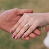 Mann hält Hand von einer Frau mit einem Verlobungsring
