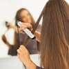 Frau glättet sich Haare