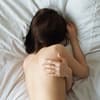 Frau schläft nackt im Bett