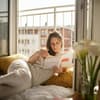 Frau liest Buch am Fenster