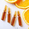 Vitamin C Seren Flakons neben Orangenscheiben