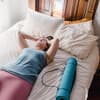Erschöpfte Frau liegt auf Bett in Sportkleidung