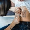 Folie vom Rippen-Tattoo wird abgezogen