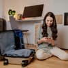 Frau sitzt auf dem Boden mit gepackten Koffern
