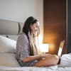 Junge Frau am Laptop im Bett
