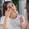 Frau deckt Augenringe mit Concealer ab