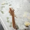 Badekugel in Hand und Badewanne