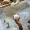 Frau hält Badekugel in der Badewanne