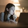 Junge Frau abends vor Laptop im Bett 