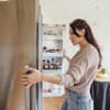 Frau schaut in den Kühlschrank