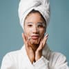 Frau im Bademantel mit Gesichtsmaske