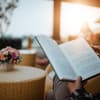 Person liest Buch auf Balkon