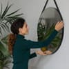 Frau hängt Spiegel an die Wand
