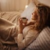 Junge Frau trink Tee im Bett 
