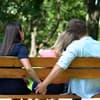 Mann hält Hand mit einer Frau hinter einer Bank