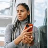 Frau hält ein Handy in der Hand und guckt traurig