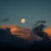 Vollmond am blauen Himmel mit orangefarbenen Wolken