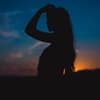 Silhouette einer Frau mit langen Haaren in der Dämmerung