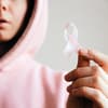 Frau mit pinkem Hoodie hält eine pinke Schleife in der Hand