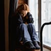 Traurige Frau sitzt auf einer Fensterbank