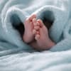 Babyfüße unter einer hellblauen Decke