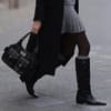 Frau trägt Stiefel und Dior-Tasche