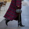 Frau mit schwarzen Stiefeln und kariertem Mantel 