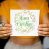 Frau hält eine Weihnachtskarte mit Weihnachtswünschen in der Hand