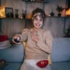 Frau sitzt auf dem Sofa und guckt in ihrer weihnachtlich dekorierten Wohnung Fernsehen