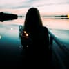 Frau steht am See mit einer Lichterkette
