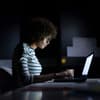Junge Frau sitzt nachts am Laptop