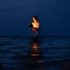 Frau steht im Meer und liest ein Buch