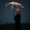 Frau hält einen Regenschirm mit Lichterketten in der Hand
