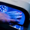 Weibliche Hand mit Nagellack unter UV-Lampe