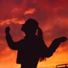 Silhouette einer Frau mit Zopf vor einem roten Himmel